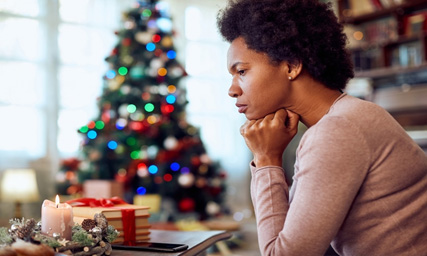 sad black woman in front of Christmas tree